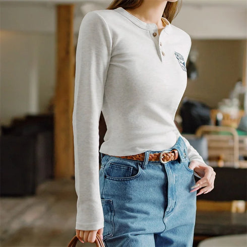 Person wearing a light gray long-sleeve shirt and blue jeans indoors.